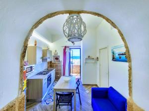 a kitchen with a table and a blue couch at Seafront House Gabbiano Blu in Santa Flavia