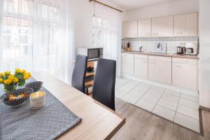 a kitchen with a wooden table with chairs and a dining room at Mayglück App 1 in Norderney