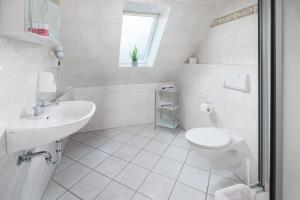 a white bathroom with a toilet and a sink at Mayglück App 3 in Norderney
