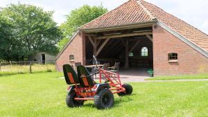 a lawn mower parked in the grass in front of a building at Dreschdiele - Landlust Osterwarf in Norddeich +3 photos