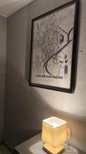 een bord op een muur boven een tafel met een lamp bij Studio L'escale Chalonnaise in Châtenoy-le-Royal