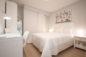 ein weißes Schlafzimmer mit einem weißen Bett und einem Schreibtisch in der Unterkunft LC Apartaments Fleming Moderno&Ubicación ideal I 3 Hab dobles I aire acondicionado in Castellón de la Plana