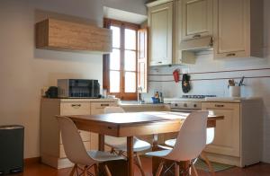 a kitchen with a wooden table and white chairs at Olive Tree Apartment in Impruneta