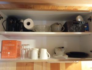 a shelf with cups and dishes on it at Le poulailler in Plancher-Bas