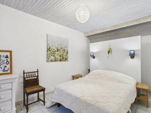 a white bedroom with a bed and a chair at Charmante maison en pierre - vue sur l'océan in Lilia