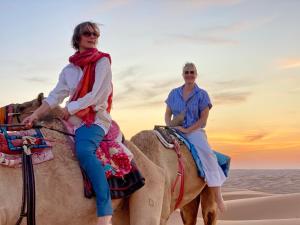 two women riding on the back of a camel in the desert at Essa camp in Wahiba Sands in Al Raka