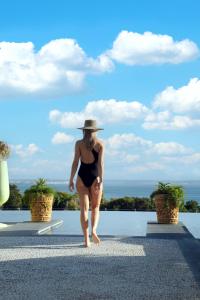 a woman in a bikini and a hat walking on a roof at El Llorenc Parc de la Mar - Adults Only (+16) in Palma de Mallorca