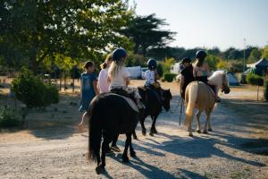 un grupo de gente montando caballos en un camino de tierra en Camping La Pointe Saint-Gildas - Maeva, en Préfailles