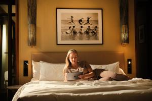 a woman sitting on a bed with a tablet at El Llorenc Parc de la Mar - Adults Only (+16) in Palma de Mallorca