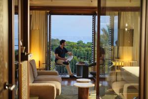 a man sitting on a balcony in a living room at El Llorenc Parc de la Mar - Adults Only (+16) in Palma de Mallorca