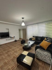 a living room with a couch and a tv at Casa de campo con piscina, aire acondicionado, estacionamiento privado con BBQ in Barranquilla