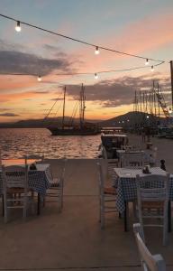 un gruppo di tavoli e sedie con una barca in acqua di Cactus luxury apartment Oreoi a Oreoi Altre 23 foto