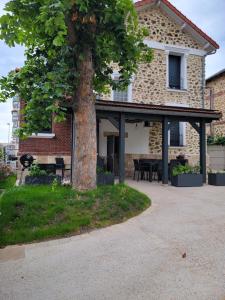 a patio with a tree in front of a house at Villa Junon in Aulnay-sous-Bois