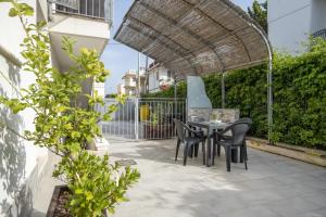 Un patio con una mesa y sillas bajo un cenador. en Gufo di Mare - Giallo, en Savelletri di Fasano