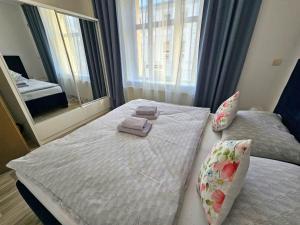 a bedroom with a bed with towels and a large window at Prostorný apartmán v centru - Wi-Fi, Netflix in Hradec Králové