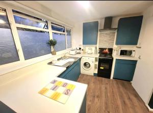 a kitchen with blue cabinets and a white counter top at Spacious Townhouse in South Norwood
