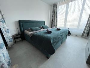 a bedroom with a green bed and a large window at DELUXE APARTMENT (Free Parking) in Trenčín