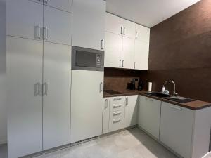 a kitchen with white cabinets and a microwave at DELUXE APARTMENT (Free Parking) in Trenčín