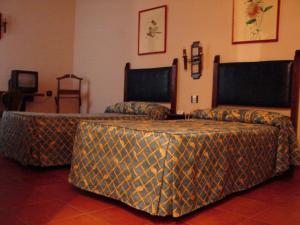 a room with two beds and a table with a blanket at Hotel Temple Pradorrey in Astorga