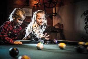 two children playing pool at a pool table at Hôtel Le Refuge in Tignes