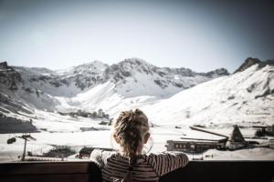 Una donna guarda una montagna coperta di neve di Hôtel Le Refuge a Tignes