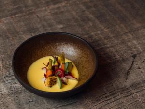 a black bowl of food with fruit on a wooden table at Boho Club in Marbella