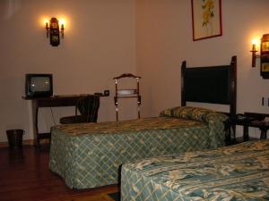 a room with two beds and a desk with a television at Hotel Temple Pradorrey in Astorga