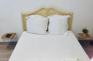 a bed with white sheets and pillows at "Pascal 1" Eglise St Louis - Studio Cosy Quartier Haut in Sète