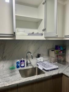 Un fregadero de cocina con un escurridor de platos al lado. en 1 BR Executive Suite Gentry Manor by JMS, en Manila