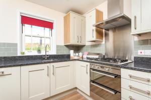 a kitchen with white cabinets and a stove at Watercress Lodges & Campsite in New Alresford