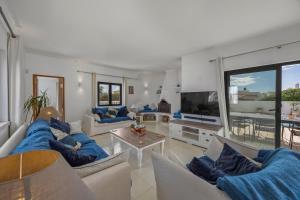 ein großes Wohnzimmer mit blauen Sofas und einem TV in der Unterkunft Casa Das Flores in Carvoeiro