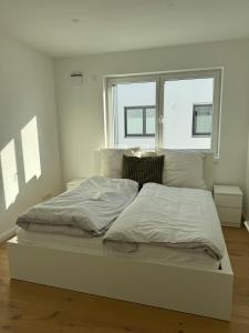 a white bed in a room with a window at New & elegant penthouse apartment in Salching