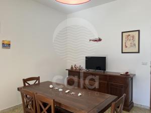 una sala da pranzo con un tavolo e una tv di Villa Sarah - Spiaggia a 20m By Cala Salento a Isola della Malva