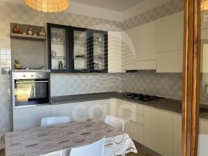 una cucina con tavolo, sedie bianche e piano cottura di Villa Sarah - Spiaggia a 20m By Cala Salento a Isola della Malva