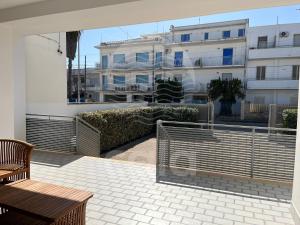 un balcone con panca in legno e un edificio di Villa Sarah - Spiaggia a 20m By Cala Salento a Isola della Malva