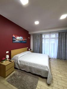 a bedroom with a large bed and a red wall at A casitta in Giardini Naxos