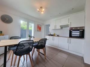 a kitchen with white cabinets and a wooden table and chairs at Le Central - Rez de jardin in Liévin