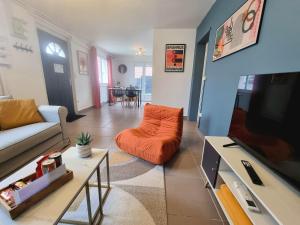 a living room with an orange couch and a tv at Le Central - Rez de jardin in Liévin