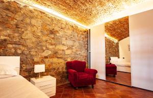 a bedroom with a stone wall and a red chair at Villa Royal B&B in Florence