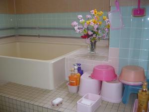 a bathroom with a tub and a vase of flowers at Minshuku Mutsukari in Furano +33 photos