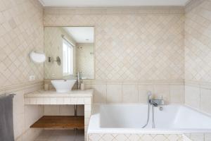 ein Badezimmer mit Badewanne, Waschbecken und Spiegel in der Unterkunft Exclusive Townhouse in Central Plaza del Duque Close to the Beach in Adeje + 19 Fotos
