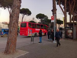 a red double decker bus on a city street at Cozzy Studio Flat in Tirana