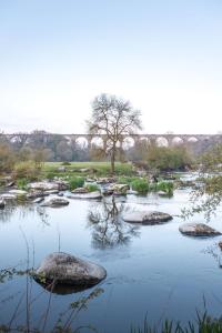 a river with rocks and a bridge in the background at La Balière T3 rénové terrasse 20min du Puy duFou in Pouzauges