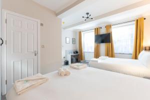 Un dormitorio blanco con dos camas y una ventana. en MARINA HOTEL London, en Londres