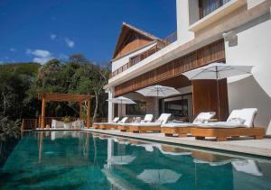 a swimming pool with chairs and umbrellas next to a building at Casa Coral, Luxury Beachfront in Higuera Blanca