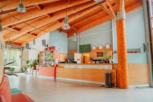 a restaurant with a counter in a room with wooden ceilings at Forum Grillensee in Naunhof