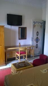 Habitación con mesa y TV en la pared. en Hotel Tiout, en Taroudant