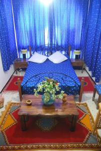 a bedroom with a bed with a table and blue curtains at Hotel Tiout in Taroudant