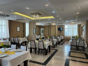 a dining room with white tables and chairs at Gabala Tufandag City Hotel in Gabala