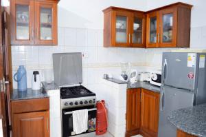 Roma Stays - Cozy 3 Bedroom Apartment with Swimming Pool in Shanzu في مومباسا: مطبخ مع موقد وثلاجة